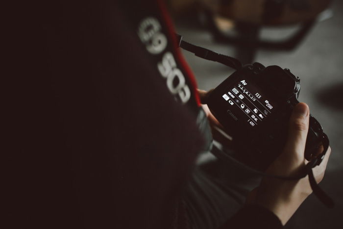 A close up of a photographer changing camera settings on a DSLR