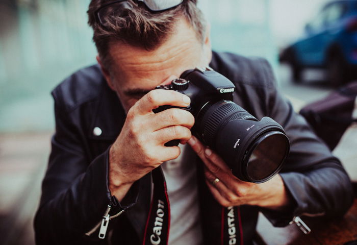 A photographer crouching to shoot a photo with his dominant eye