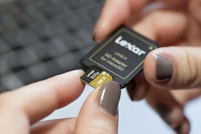 A close up of a photographer loading a Micro Secure Digital High Capacity into an adapter