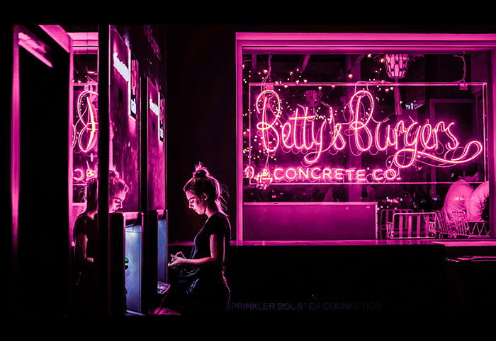 A portrait of a female model surrounded by hot pink neon lights