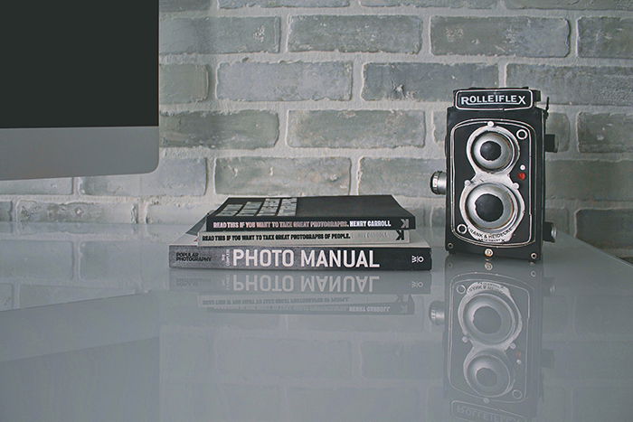 A still life featuring photography books and a rolliflex camera on a table