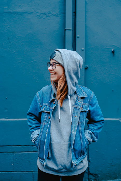 A portrait of a female model posing against a blue wall 