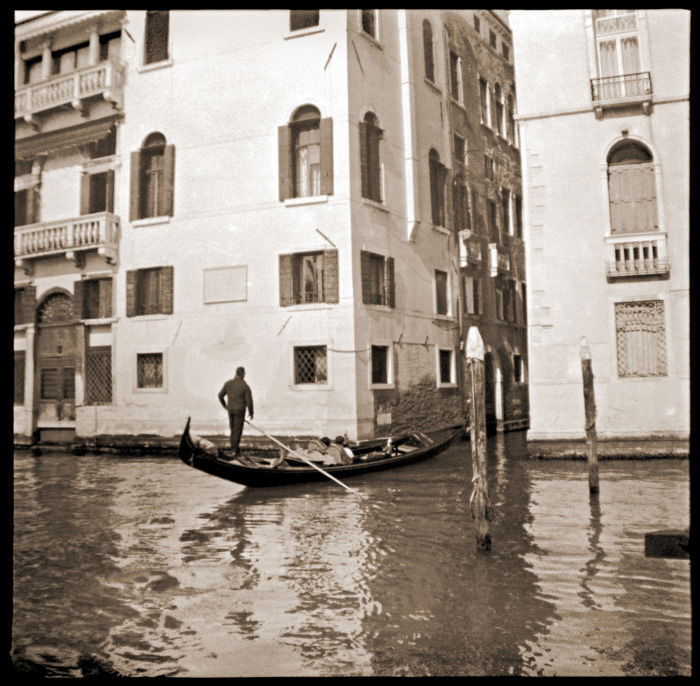 A black and white caffenol photo of a man in a gondola in Venice 