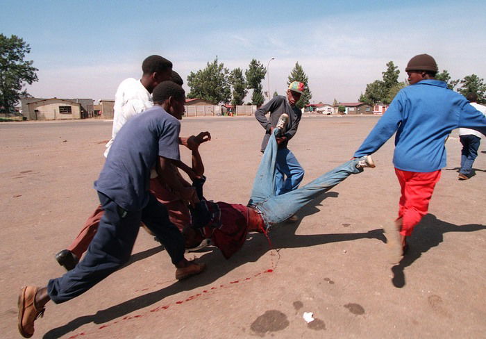 An image of 5 men carrying a bleeding man by war photographer João Silva