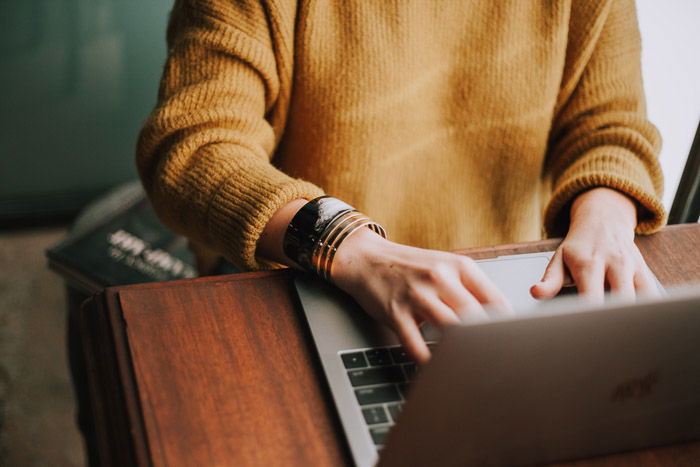 A close up of a person working on a laptop - zenfolio vs Smugmug review