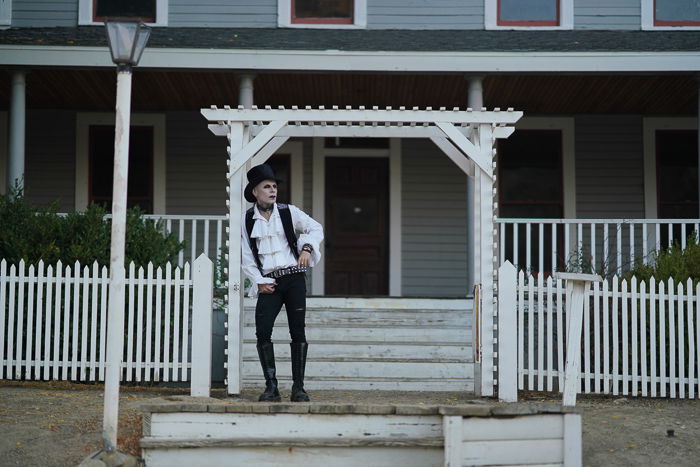 A portrait of a gothic style male model posing in front of a house - photography laws