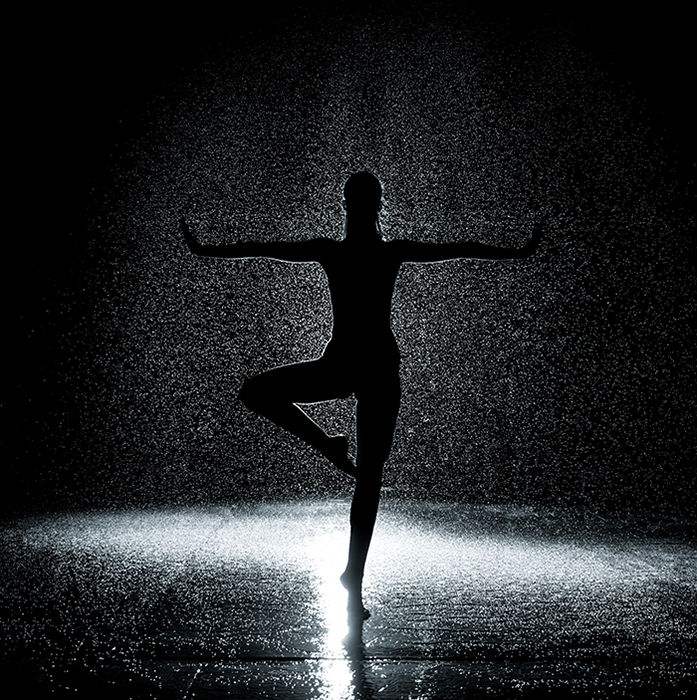 Artistic ballet photography shot of the silhouette of a female ballerina dancing onstage in low light