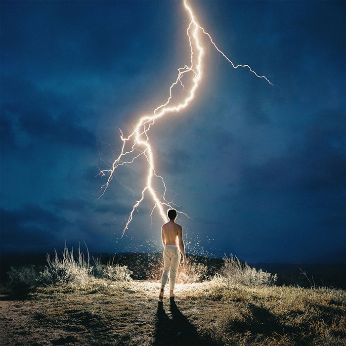 A man standing under a lightning bolt by fine art photographer Alex Stoddard