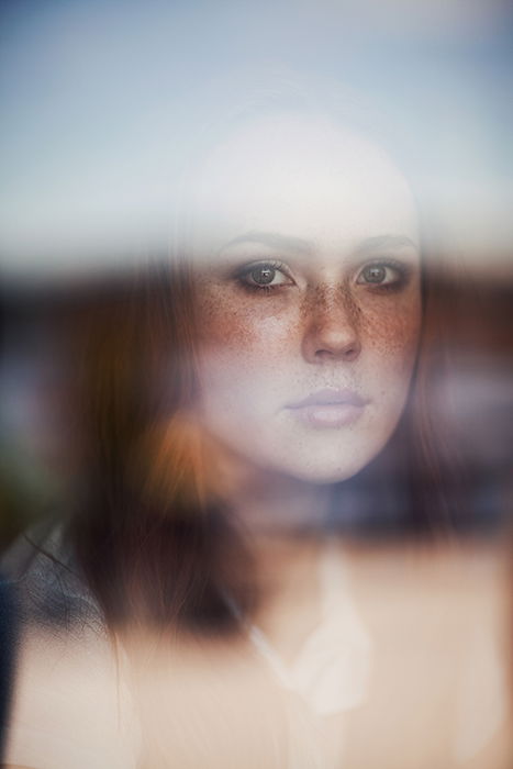 Ethereal portrait of a female model through a window with a blurry reflection by fine art photographer Ruby James