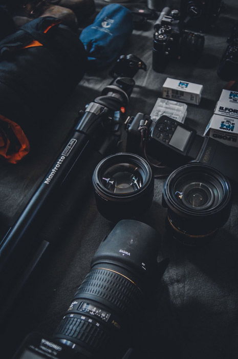 Camera lenses, tripod and other photography equipment of a black table