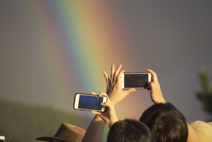 Two people taking rainbow photography with their smartphones