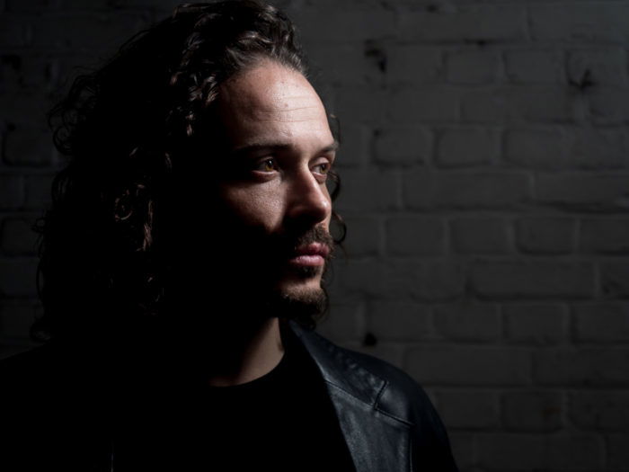 A dark and moody portrait of a male model shot with Rembrandt lighting