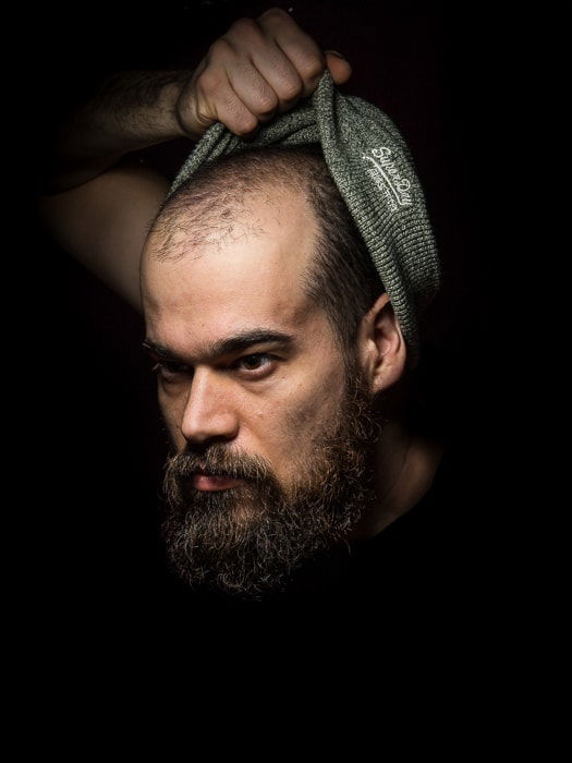 A dark and moody portrait of a male model shot with Rembrandt lighting