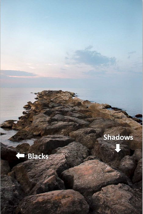 A stunning coastal landscape with arrows pointing out shadows and blacks in the rocks