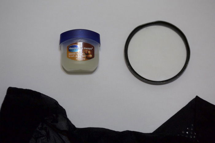 A flat lay of vaseline, lens filter and black stocking on white background - soft focus photography 