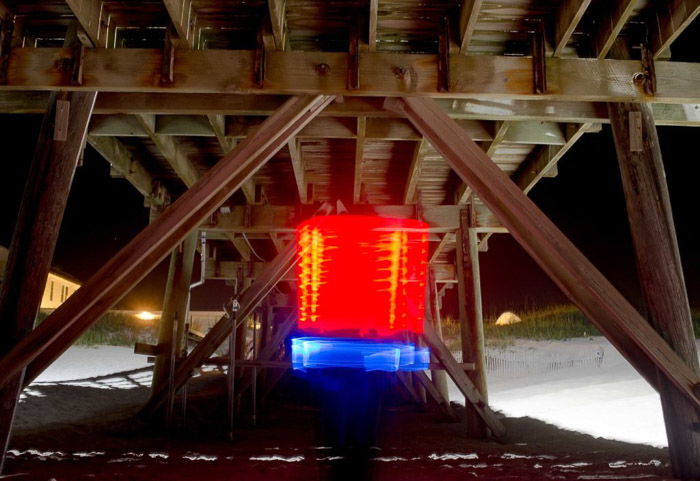 Blue and red light painting shot under a wooden structure at night using LED light painting tools