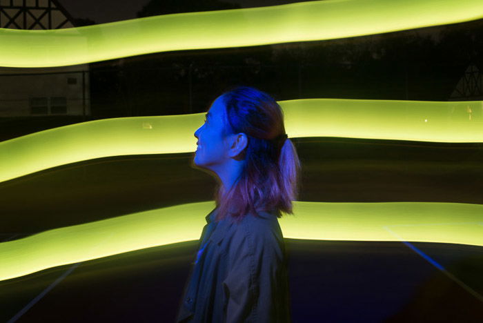 A portrait of a female model posing in from of neon green streaks of light