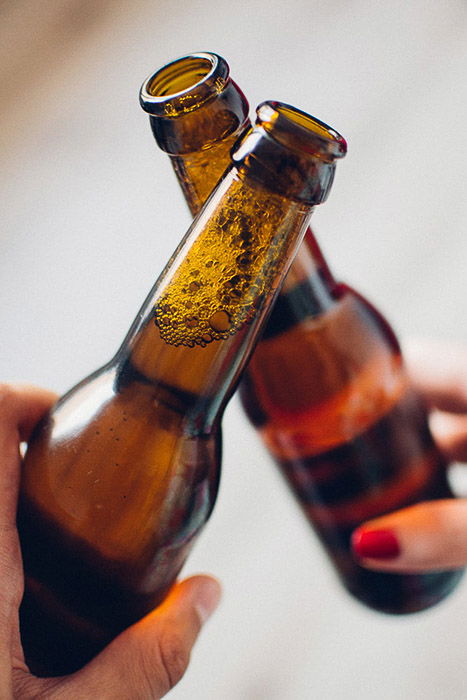 Beer photography shot of two people clinking glasses indoors