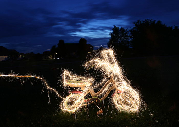 A bicycle surrrounded by light painting, outdoors at night, shot using LED light painting tools