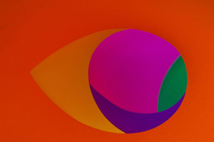 A creative abstract photo using 5 sheets of colored paper - magenta, yellow, green, and purple sheets are rolled to look like circles