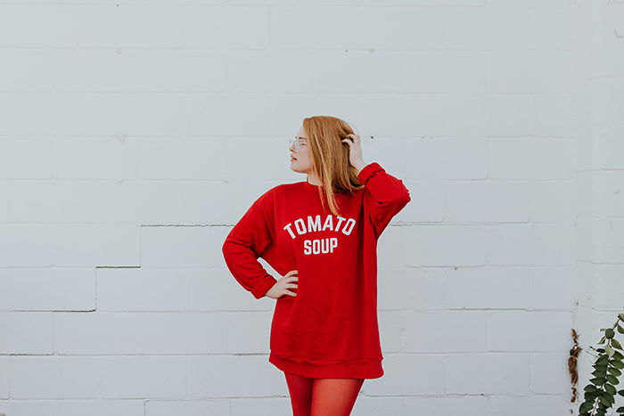 Bright portrait of a female model in red posing against a white wall