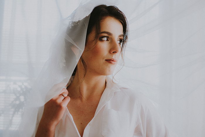 Dreamy portrait of a female model posing indoors with a white veil