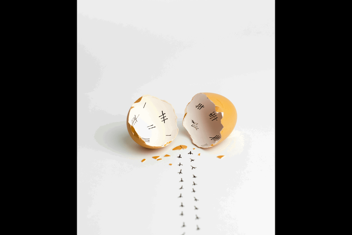 A unique funny composed conceptual still-life scene made from a cracked egg shell and ink as an example for Easter picture ideas