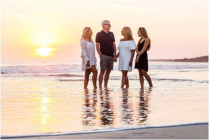 Asweet portrait of a family of four posing on the beach at sunset- emotional photography