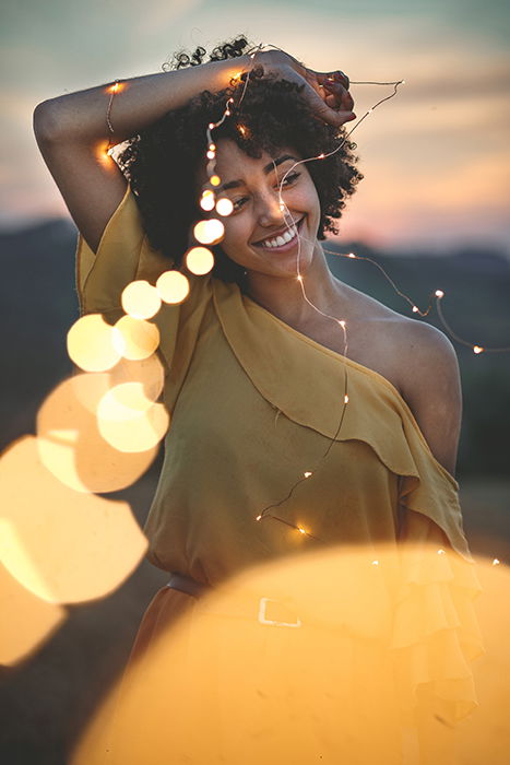 A creative outdoor portrait of a female model holding a string of lights - fairy light photography 