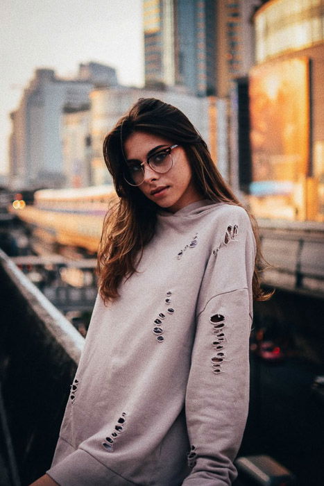 A lookbook fashion shot of a female model posing against a wall outdoors - fashion photography types