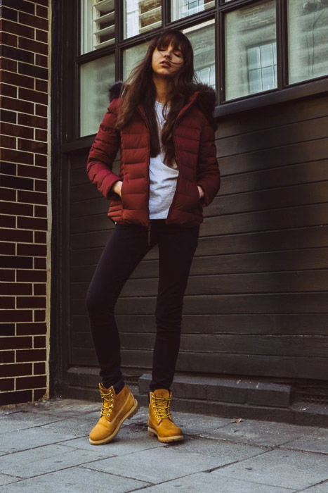 A street style fashion shot of a female model posing against a window outdoors - fashion photography types