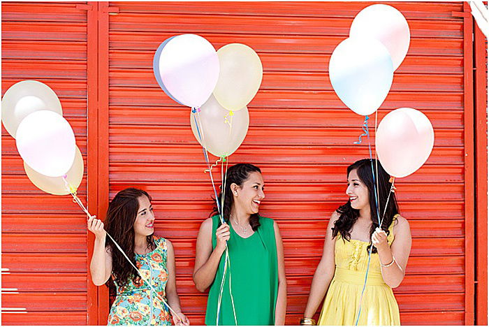 Three women posing for a photo with balloons. 