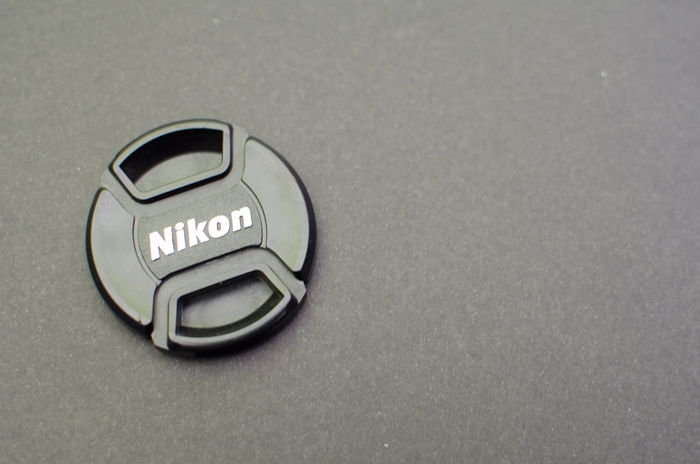 A Nikon lens cap on grey background - grey card photography