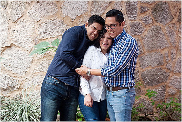 Three friends smiling, laughing and embracing posing outdoors - emotional photography