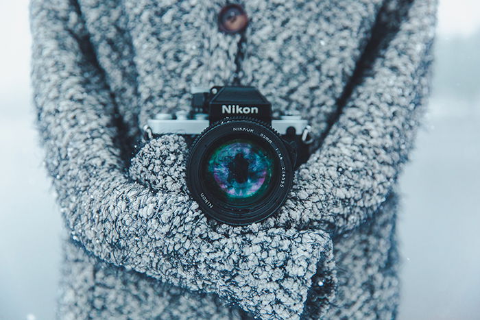 A close up of a Nikon camera around the neck of a photographer, shooting snow portraits