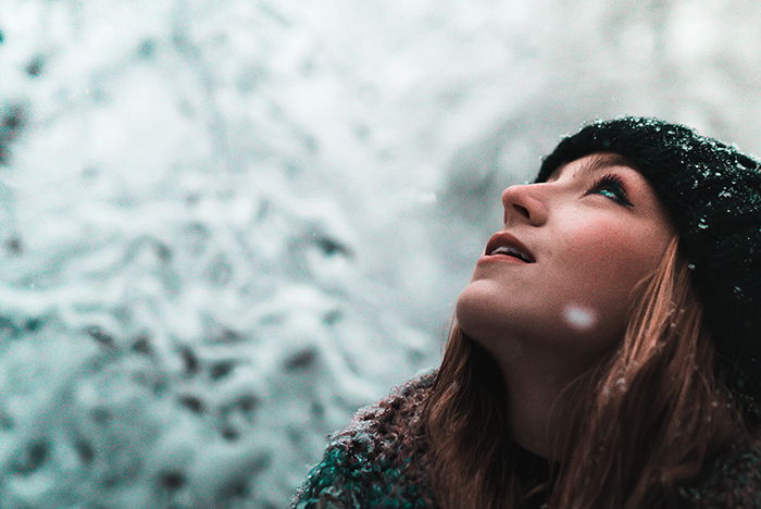 Close up winter portrait photography of a female model posing in the falling snow