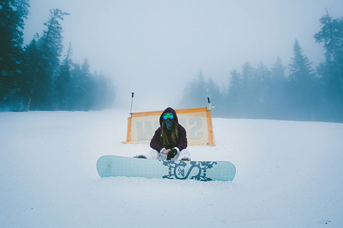 Atmospheric snow portraits of a female snowboarder posing in a winter landscape