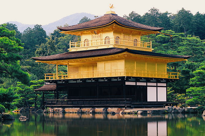 The gold covered temple of Kinkakuji in Kyoto,next to a forest and a pond. Japan photography tips 