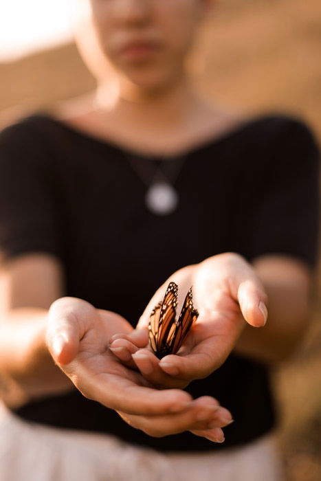 A portrait of a model holding a butterfly, shot with a wireless flash trigger