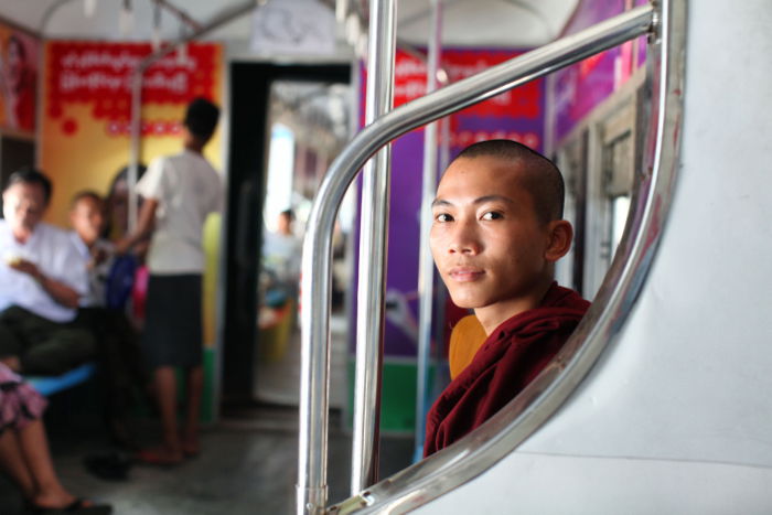 Portrait of a Buddhist monk sitting in the interior of a train 