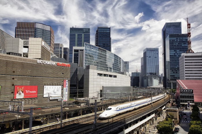 A modern ttrain moving through a large city