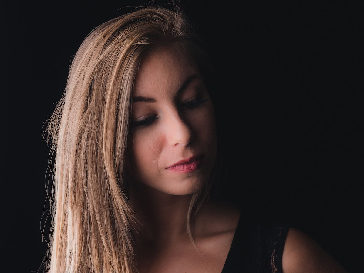 An indoor studio photo of a woman with a dark back ground and shadows using broad portrait lighting