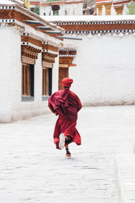 The decisive moment of a young monk running through a street in Ladakh