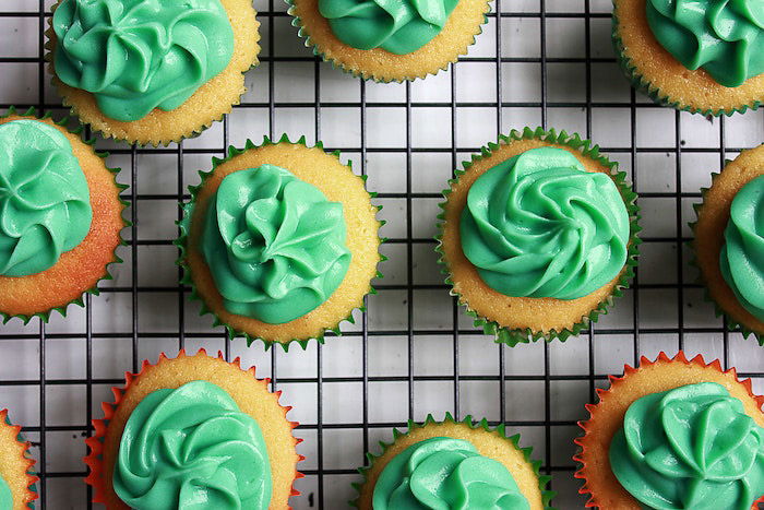 Overhead cup cake photo of a plate of green frosted cakes on a wire rack 