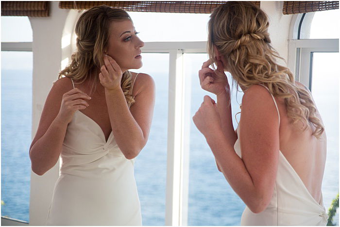 A wedding portrait of a bride fixing her earrings in a mirror - wedding flash photography