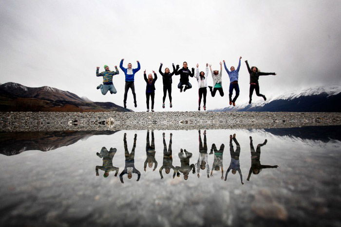 A group jumping in front of a body of water 