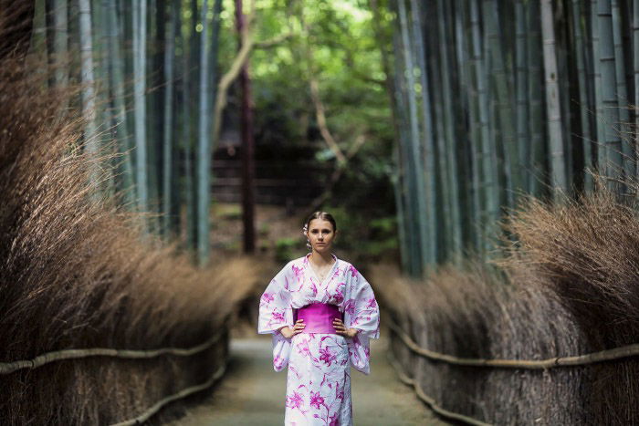 A holiday portrait of a female model in asian style dress posing in a forest