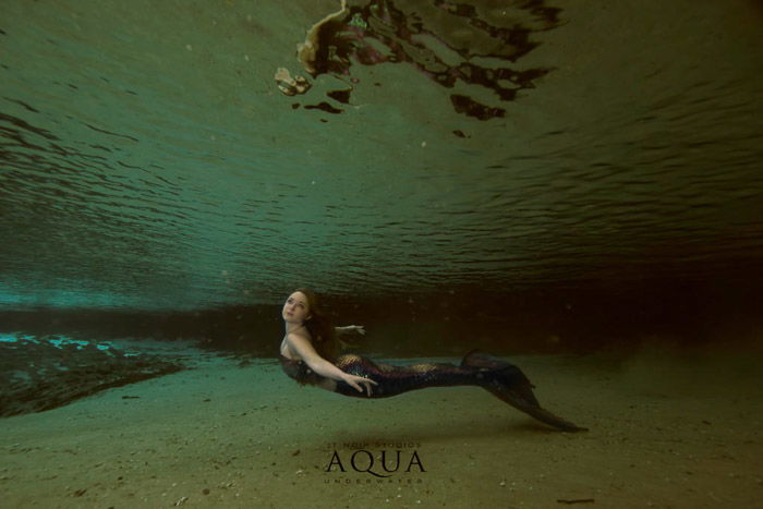 A magical underwater mermaid photoshoot featuring a female model with mermaid tail swimming underwater