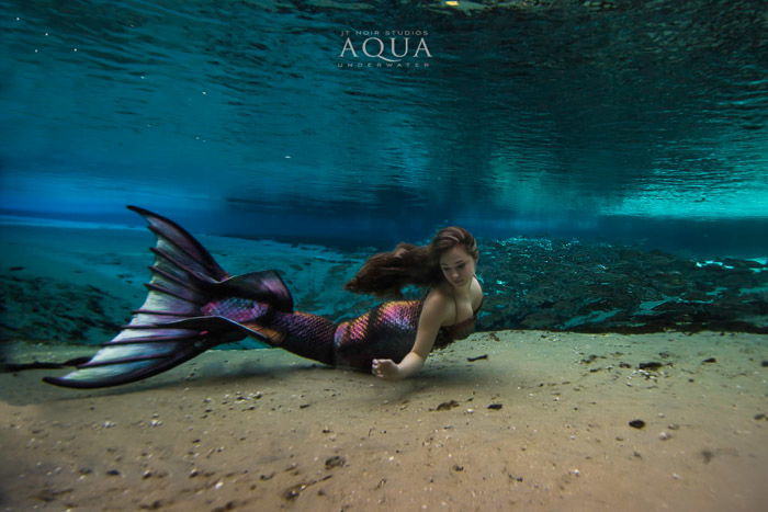 A magical underwater mermaid photoshoot featuring a female model with mermaid tail swimming underwater