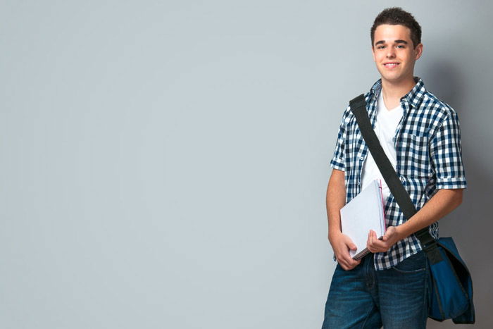 A school portrait of a Smiling teenager with a schoolbag standing on wall background - tips for quality school portraits